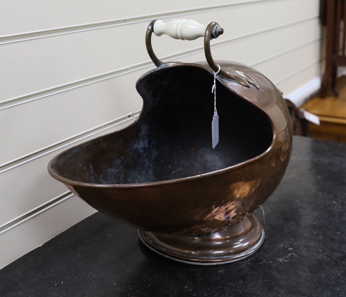 A helmet shaped copper coal scuttle, with ceramic handles, 52cms wide